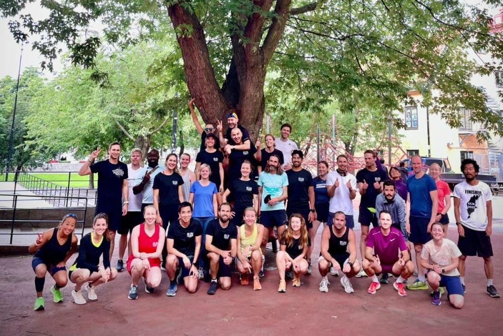 The Run Collective Stockholm group gathered under a large tree in a Stockholm park.