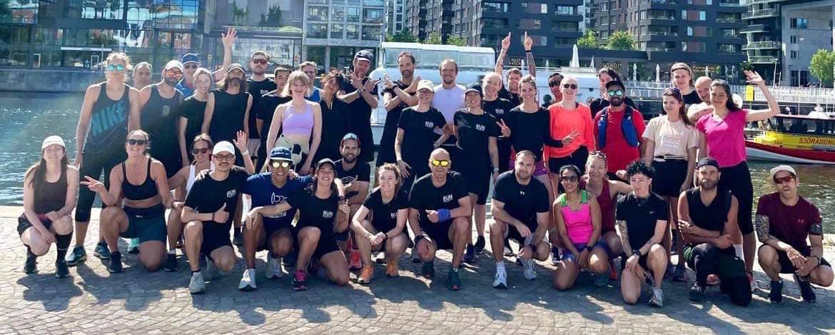 The Run Collective Stockholm group posing by the water on a sunny day.