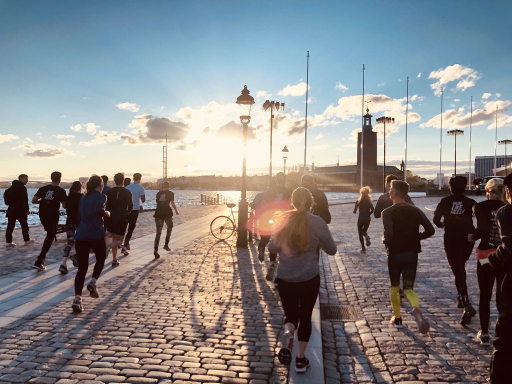 A group of runners heading along the Stockholm waterfront at sunset, with Stadshuset on the skyline.